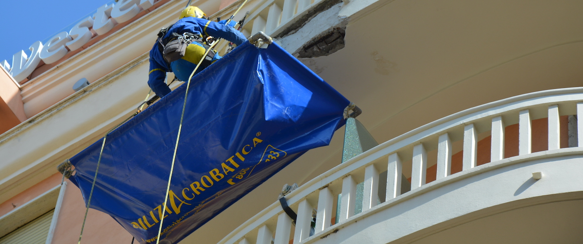 Muratore di Ediliziacrobatica che ripara un balcone con dettaglio della parte da ristrutturare 