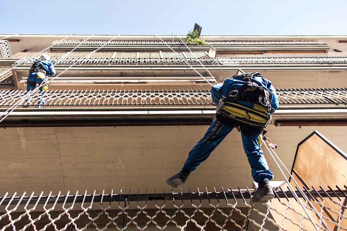 Ristrutturazione di un balcone con Acrobatica. Operai su fune, prospettiva dal basso, con bonus balconi 2023