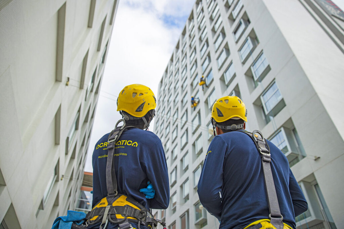 Finanziamento al condominio immagine esemplificativa: due operai acrobatica di spalle che guardano due condomini