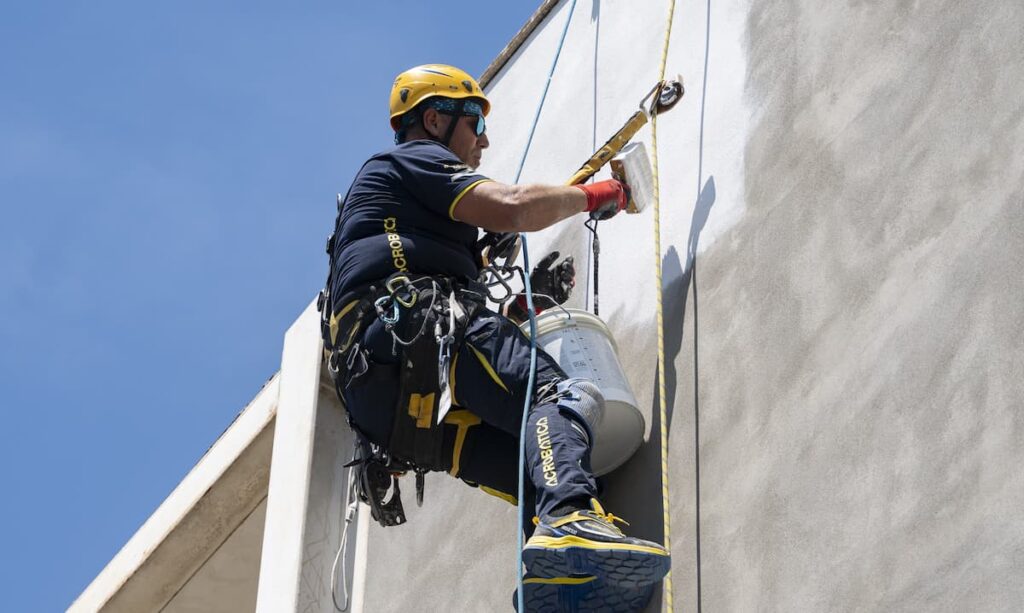Operaio di acrobatica su fune davanti a una facciata